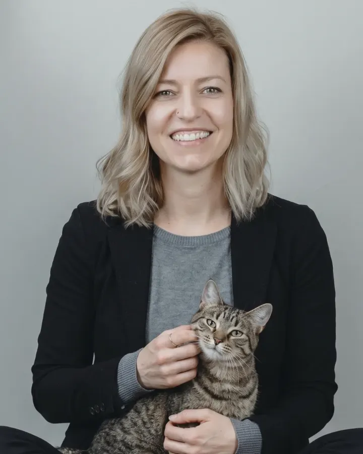 Larissa Rüncos, médica veterinária, sorrindo com um gato no colo